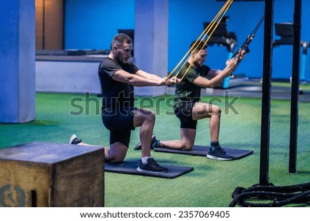Two men working out with rubber bands and body weight at the gym Royalty-Free Stock Photo #2357069405