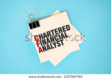 Text CHARTERED FINANCIAL ANALYST on sticky notes with copy space and paper clip isolated on red background.Finance and economics concept.