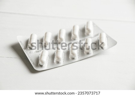 White pills in blister pack close-up on light table, background with copy space