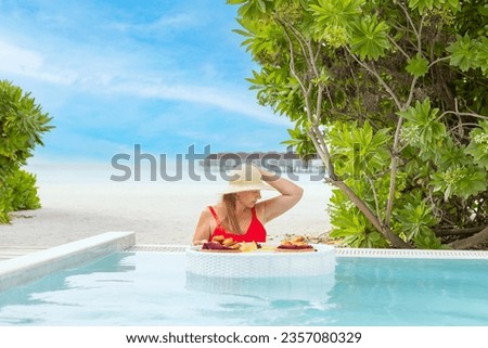 plus size young woman with served floating tray in swimming pool with drinks and snacks on tropical island resort in Maldives, cocktails and canapes for romantic date in luxury hotel, travel concept