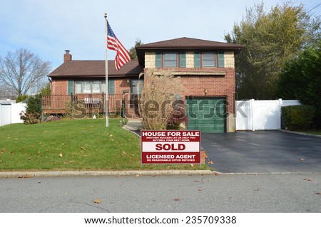 American flag pole Real Estate sold (another success let us help you buy sell your next home ) sign suburban home back split snout style in residential neighborhood USA