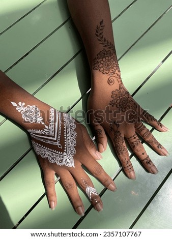 Traditional henna art tattoo on the hands. Classic brown and modern white mehendi. Bridal mehndi. Indian wedding tradition. Minty green wooden background.