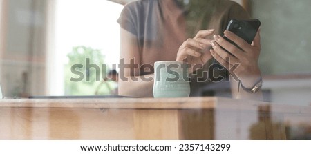 Business woman using mobile phone during working remotely on laptop in coffee shop, surfing the internet, social network, online shopping, digital banking, people lifestyle concept