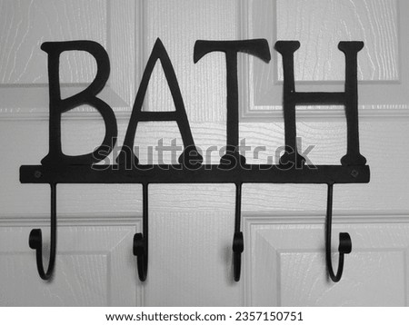 Bathroom wall hanger with multiple hooks and the word bath