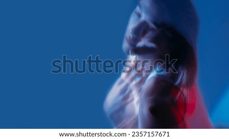 Depressed face. Color light portrait. Double exposure of unhappy unsmiling woman with soul pain isolated on neon blue empty space background. Royalty-Free Stock Photo #2357157671