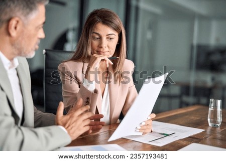 Two financial experts discussing accounting tax documents in office. Lawyer consulting older client investor showing papers at meeting. Mature business executive colleagues doing paperwork overview. Royalty-Free Stock Photo #2357193481