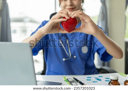Female doctor holding heart shaped red ball explaining to patient online on laptop computer Concept of cardiology, health services, medical