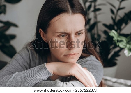 Close up portrait sad lonely woman sitting on sofa alone at home looks frustrated feel worried suffers from break up, psychological concerns, need professional counsellor help, think about problems Royalty-Free Stock Photo #2357222877