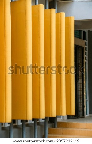 The yellow wall in front of the campus building stands out from the side