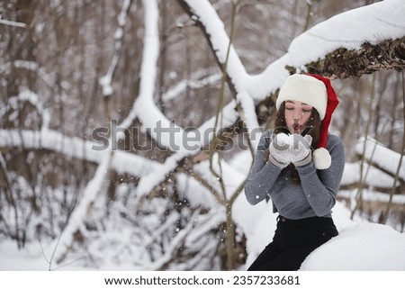 A young girl in a winter park on a walk. Christmas holidays in the winter forest. Girl enjoys winter in the park.
