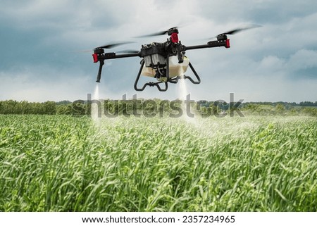 Modern technologies in agriculture. An industrial drone flies over a green field and sprays useful pesticides to increase productivity and destroys harmful insects. increase productivity Royalty-Free Stock Photo #2357234965