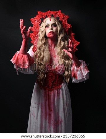 Close up portrait of  scary vampire zombie queen, wearing elegant halloween fantasy costume . Isolated on dark studio background with gestural hands reaching out towards camera.