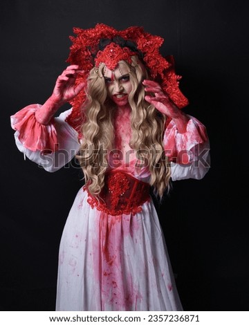 Close up portrait of  scary vampire zombie queen, wearing elegant halloween fantasy costume . Isolated on dark studio background with gestural hands reaching out towards camera.