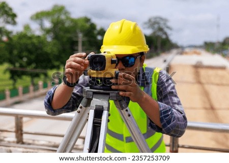Surveyor engineer wearing safety uniform and helmet with equipment theodolite to measurement positioning on the construction site of the new road