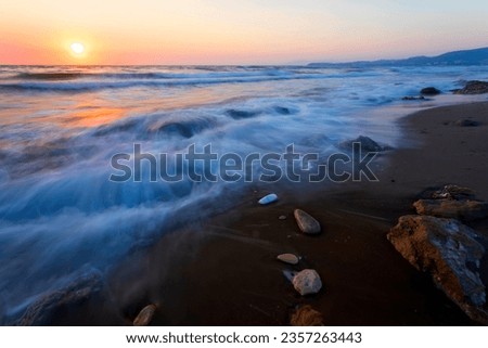 A seascape photographed with a long exposure technique at sunset.