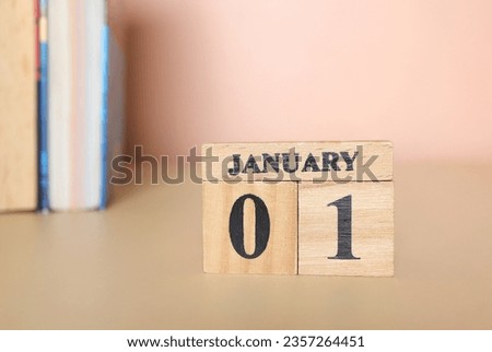 Start new year 2024. Wooden calendar with 1 january word with copy space. Cube calendar with date January 1st and books on the table.