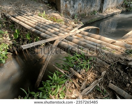 small bridge made of bamboo, over a small river.