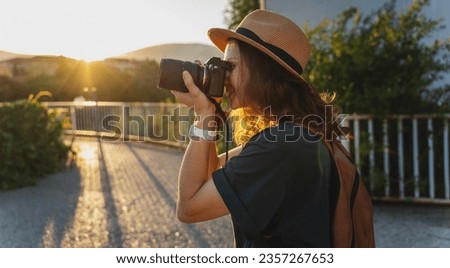 Young caucasian woman traveler in a hat with a photo camera in her hands in a summer city