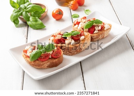 Tray of delicious caprese bruschette, a typical italian appetizers with mozzarella, tomato, basil, black olives, oregano and olive oil  Royalty-Free Stock Photo #2357271841