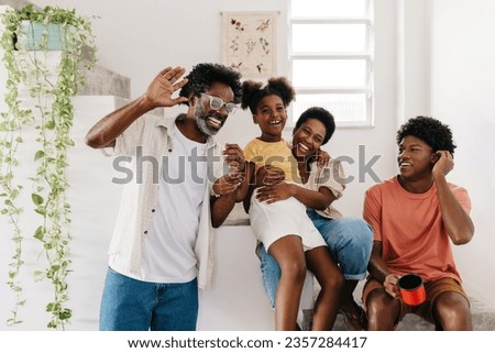 Mature black man smiling and having a fun time with his family at home. Husband and father spending quality time with his wife and two children, creating a happy home full of smiles positive vibes. Royalty-Free Stock Photo #2357284417