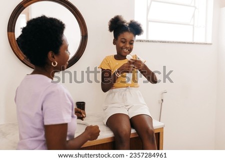 Mother and daughter engage in their daily oral hygiene routine at a bathroom sink. Woman guiding her young child in brushing teeth, teaching the importance of personal hygiene and a healthy lifestyle. Royalty-Free Stock Photo #2357284961