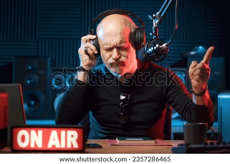 Radio host working in the radio broadcasting studio, he is on air and enjoying the music