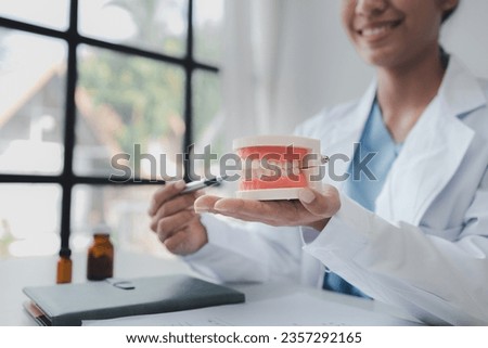 Female dentist with dentures for explaining teeth, recommending orthodontic guidelines, dentist consulting patient's symptoms and endodontic treatment. Dental treatment concept. Royalty-Free Stock Photo #2357292165
