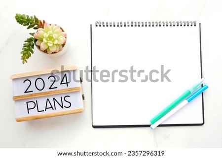 2024 plan on wood box, blank notebook paper on white marble table background, 2024 new year mock up, template with copy space for text, top view