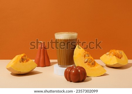 Pumpkin coffee in glass and pieces of pumpkin on orange background