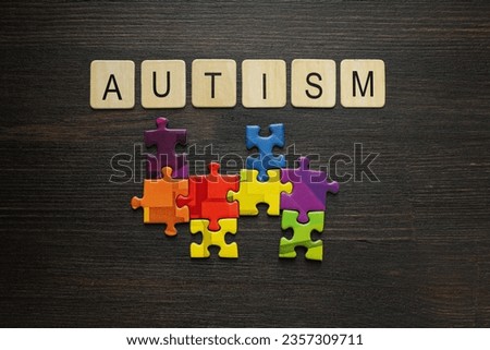Multicolored puzzle pieces with the word "autism" on a black background. World autism day concept
