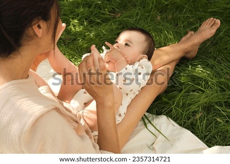 Close-up of a mother gently caressing her newborn's tiny feet and giving them a loving kiss Royalty-Free Stock Photo #2357314721