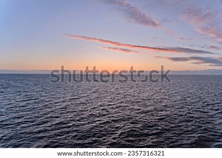 Beautiful sunset on the Skagerrak North Sea with blue orange yellow sky and clouds, colorful sky reflected in the water. Summer twilight evening on the Norwegian coast. Royalty-Free Stock Photo #2357316321