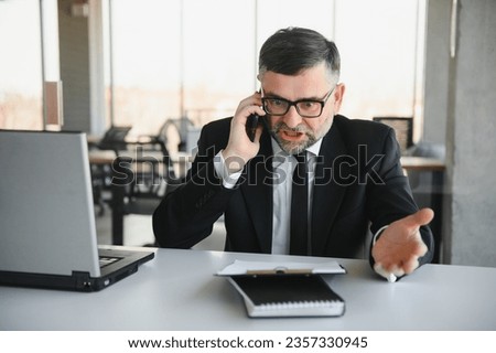 Angry manager throwing away his phone in his office. Royalty-Free Stock Photo #2357330945