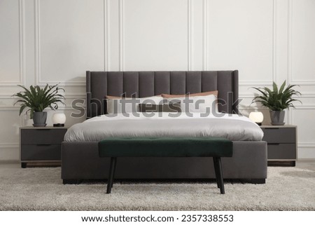 Stylish bedroom interior with large comfortable bed and ottoman Royalty-Free Stock Photo #2357338553
