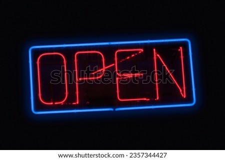 Close-up on a neon light shaped into a blue rectangle and the word "open" in red.