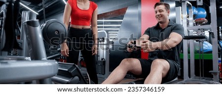 Coach woman guiding workout with hands muscles stretch with equipment machine with man in fitness gym club, strength and flexibility training, man exercise with trainer or partnership, sport concept.