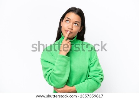 Young Colombian woman isolated on white background having doubts while looking up