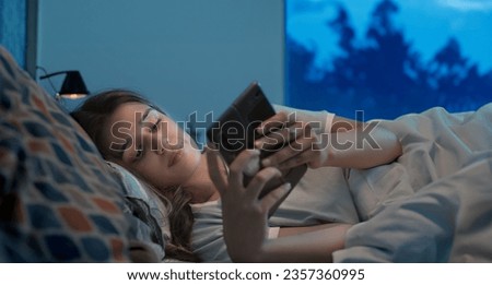 Indian upset sad alone woman crying lying on bed using mobile phone chatting late night at indoor home. Lonely unhappy female looking on smartphone screen typing reading bad massage at inside house Royalty-Free Stock Photo #2357360995