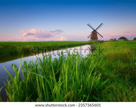 An old mill in the Netherlands. Historical building. A mill near a canal. Dutch architecture and history. Photo for postcard or background.