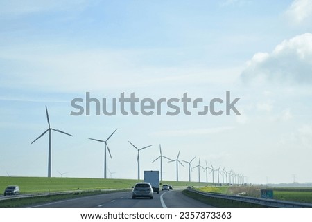 Wind farm turbines (windmill park) station next to the road in the Netherlands, Europe, using for sustainable green ecological power energy generation and renewable (repower) energy for electricity Royalty-Free Stock Photo #2357373363