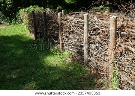 The dead hedge is located in the vicinity of the Wuhle River in the recreation area of Berliners. A dead hedge is a barrier constructed from cut branches, saplings, and foliage. Berlin, Germany Royalty-Free Stock Photo #2357403363