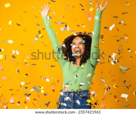 Studio Shot Of Excited Woman Celebrating Big Win Showered In Tinsel Confetti On Yellow Background Royalty-Free Stock Photo #2357421961