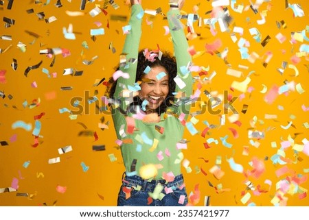 Studio Shot Of Excited Woman Celebrating Big Win Showered In Tinsel Confetti On Yellow Background Royalty-Free Stock Photo #2357421977