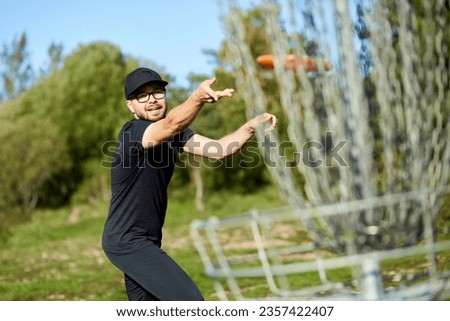 Man is throwing disc to the basket in disc golf Royalty-Free Stock Photo #2357422407