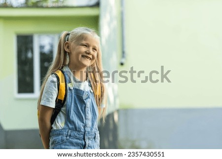 Cute smiling little girl with backpack on a greenery background. Education concept. First grader portrait.Mental health of a school chlidren.