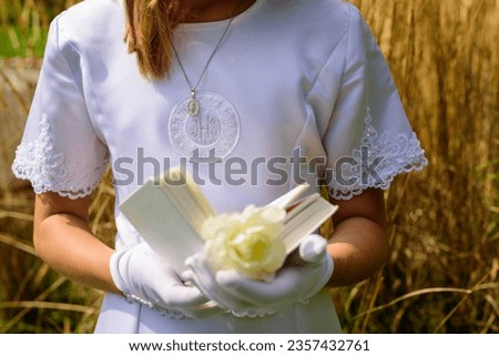 hands of a first communion girl holding a prayer book. First Holy Communion. A girl in a white communion dress. hands of a first communion girl, in white gloves, holding a Bible. outdoor prayer. Royalty-Free Stock Photo #2357432761