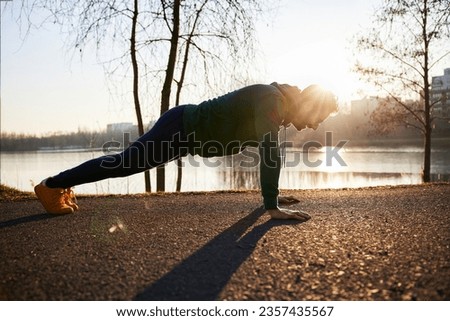 Adult man doing push ups exercise outdoors in urban environment  Royalty-Free Stock Photo #2357435567