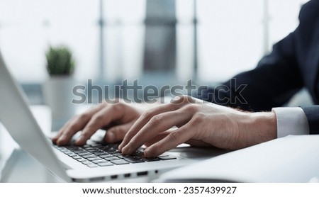 Closeup image of a man working and typing on laptop computer keyboard