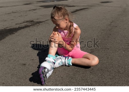 school girl roller skate beginner looking at bleeding knee. consequences dangerous roller skating without protective equipment Royalty-Free Stock Photo #2357443445