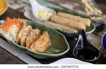 a photography of a table with a plate of food and a pair of scissors, plate of food with a spoon and a bowl of dipping sauce.